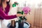Woman spraying blooming orchid with water in living room. Housewife takes care of home plants and flowers