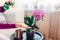 Woman spraying blooming orchid with water in living room. Housewife takes care of home plants and flowers