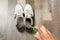 Woman spraying deodorant over pair of shoes at home, closeup