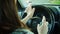 Woman spraying disinfectant and cleaning steering wheel with wet wipes