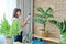 Woman spraying indoor plants at home using spray bottle with fertilized water