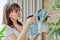 Woman spraying indoor plants at home using spray bottle with fertilized water