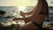 Woman is spraying sunscreen lotion on skin of hand sitting on beach sea