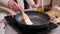Woman spreading butter on the hot frying pan with a silicone brush