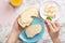 Woman spreading butter on slice of bread over table