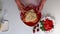 A woman is spreading cream on a biscuit. Next to the saucer is a strawberry and there is a cream.