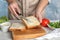 Woman spreading sauce on sandwich at grey marble table, closeup