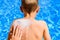 Woman spreads sunscreen on a child`s back in summer to avoid sunburn