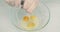 Woman Sprinkling Black Pepper On Egg Yolks In Bowl