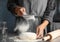 Woman sprinkling dough for pastry with flour