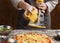 Woman sprinkling pizza with cheese, rubbing on grater