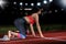 Woman sprinter leaving starting blocks on the athletic track. exploding start on stadium with reflectors