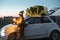 Woman with sprklers near car and Christmas tree outdoors