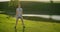 A woman squats with dumbbells at sunset in a park against the backdrop of a river. Outdoor training.