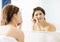 Woman squeeze her acne in front of the mirror