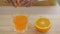 Woman is squeeze juice from an orange into glass
