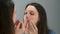 Woman squeezes out pimples on her face in front of the mirror at home.