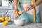 Woman squeezing fresh lemon juice with wooden reamer into bowl