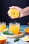 Woman squeezing fresh orange juice on blue table, top view