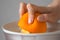 Woman is squeezing oranges using electric juicer in the kitchen, hand closeup.