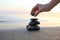 Woman stacking dark stones on sand near sea  for text