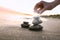 Woman stacking dark stones on sand near sea. Zen concept