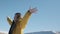 Woman stand on mountain top with hands up on sunset sky. Snow-covered mountains. Woman in a yellow jacket enjoys freedom