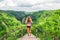 Woman stand on overhanging bridge on high cliff above jungle