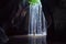 Woman stand under cave waterfall