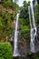 Woman stand under Sekumpul waterfall, see on falling water