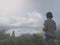 A woman standing alone in the fog with hot a cup of coffee or tea in hands, looking at the lake view. Enjoying the misty morning