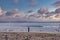 Woman standing with arms raised surrounded by seagulls on sand at beach