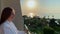 Woman standing on a balcony at the sunrise and enjoying the sea view , turn around and cheerfully smiling.