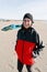 Woman standing on the beach, smiling after riding kite on cold windy day.