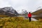 Woman standing at Beautifil Alpine Lake surrounded by Snowy Mountains