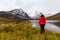 Woman standing at Beautifil Alpine Lake surrounded by Snowy Mountains