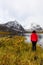Woman standing at Beautifil Alpine Lake surrounded by Snowy Mountains