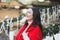 Woman standing on Christmas decorated porch of house  and drinking hot chocolate