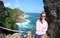 A woman is standing on a cliff with the background of the vast ocean.