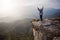 Woman standing on cliff with outstretched arms