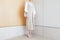 Woman standing in corner beige dress with mid heel shoe minimal trendy style.