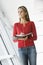 Woman standing in corridor writing in notebook