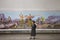 Woman standing in front of socialist realist mosaic at Pyongyang Metro in North Korea