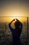 Woman standing on high building roof and making heart shape finger cover beautiful sunset sky