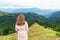 Woman standing on hill and looking at mountains with forests