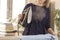 A woman is standing at an ironing board and holding an iron from which steam escapes. Woman during household chores. Ironed clothe