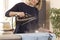 Woman is standing at an ironing board and holding an iron from which steam escapes. Woman during household chores. Ironed clothe