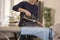 A woman is standing at an ironing board and holding an iron from which steam escapes. Woman during household chores. Ironed clothe