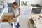 Woman standing in kitchen chopping vegetables, full length