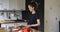 Woman standing in kitchen cuts cherry tomatoes for vegetarian salad